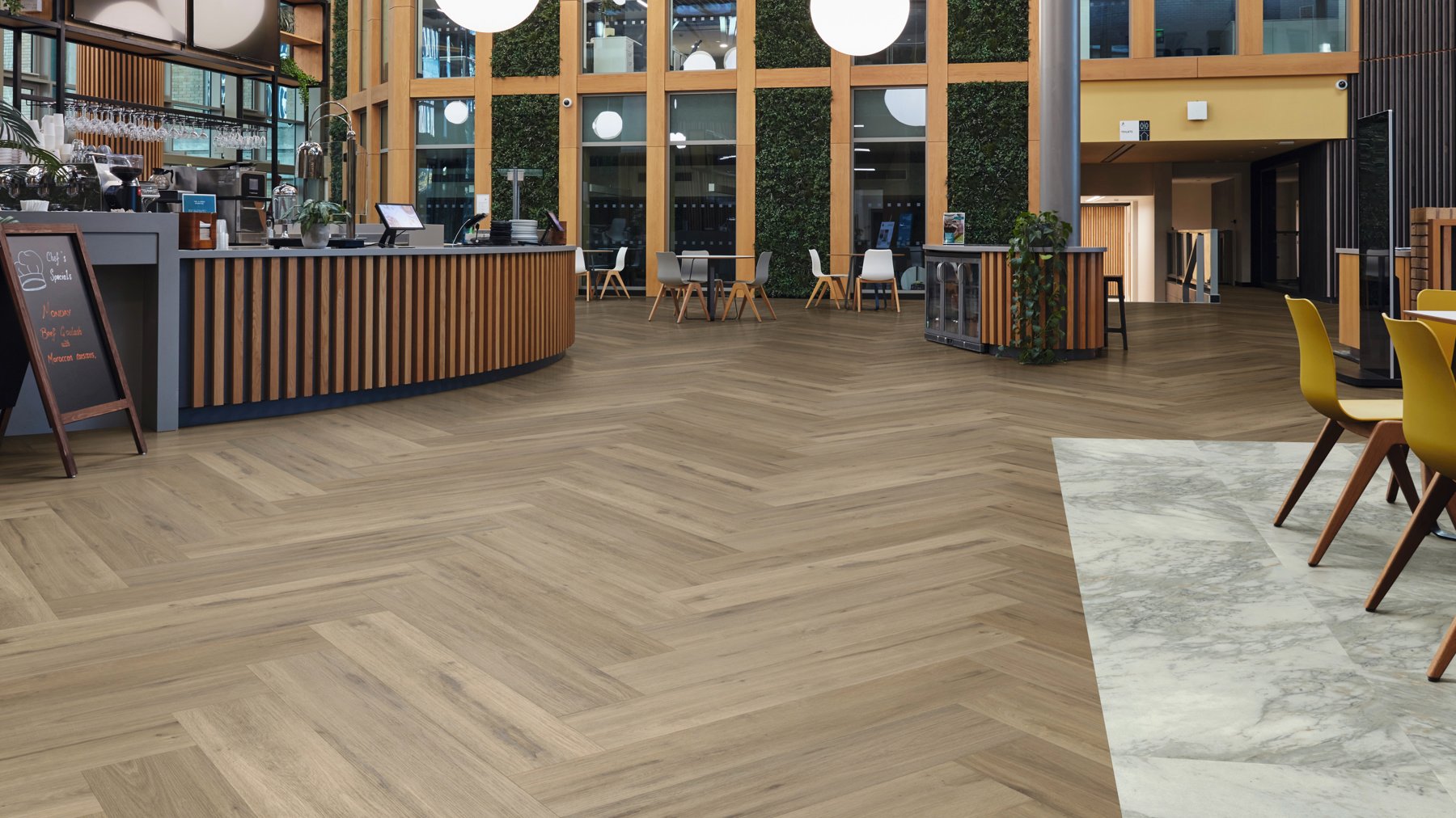 Herringbone Leyster Oak lvp floors create a walking path around the cafe seating area with Sillano Marble lvt flooring